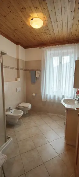 Bagno luminoso con soffitto in legno e sanitari sospesi
