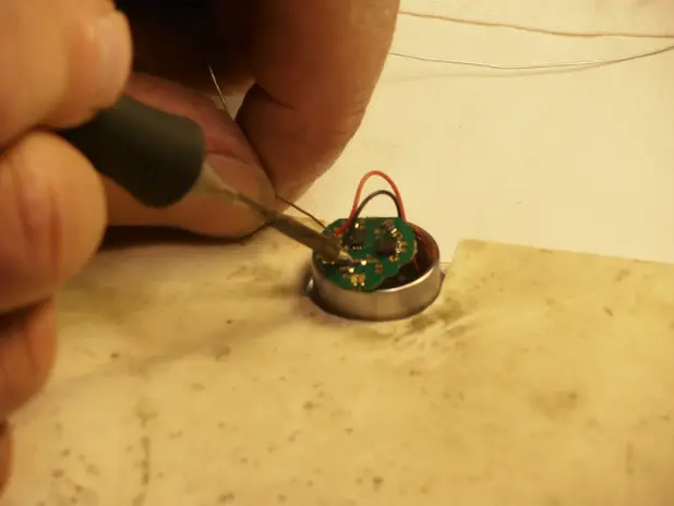 Tecnico che esegue una saldatura su un piccolo circuito elettronico.