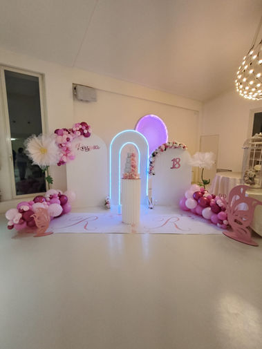 Allestimento per eventi con archi luminosi e palloncini rosa.