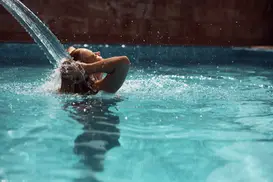 Donna che riceve un massaggio cervicale sotto il getto d'acqua in piscina