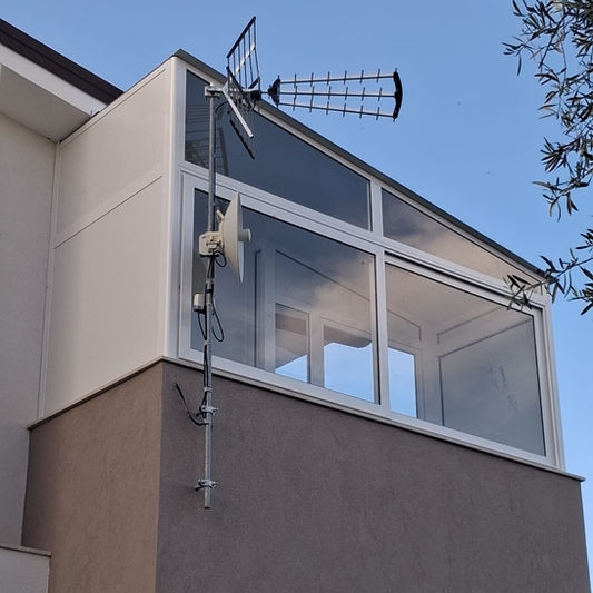 Veranda in alluminio con ampie vetrate su un balcone.