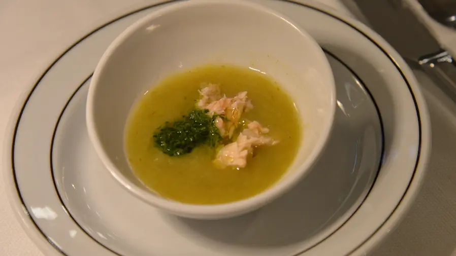 Zuppa di verdure con guarnizione in ciotola bianca.