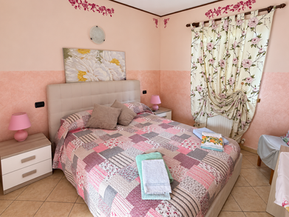 Camera da letto accogliente con pareti rosa e piumone a quadri.