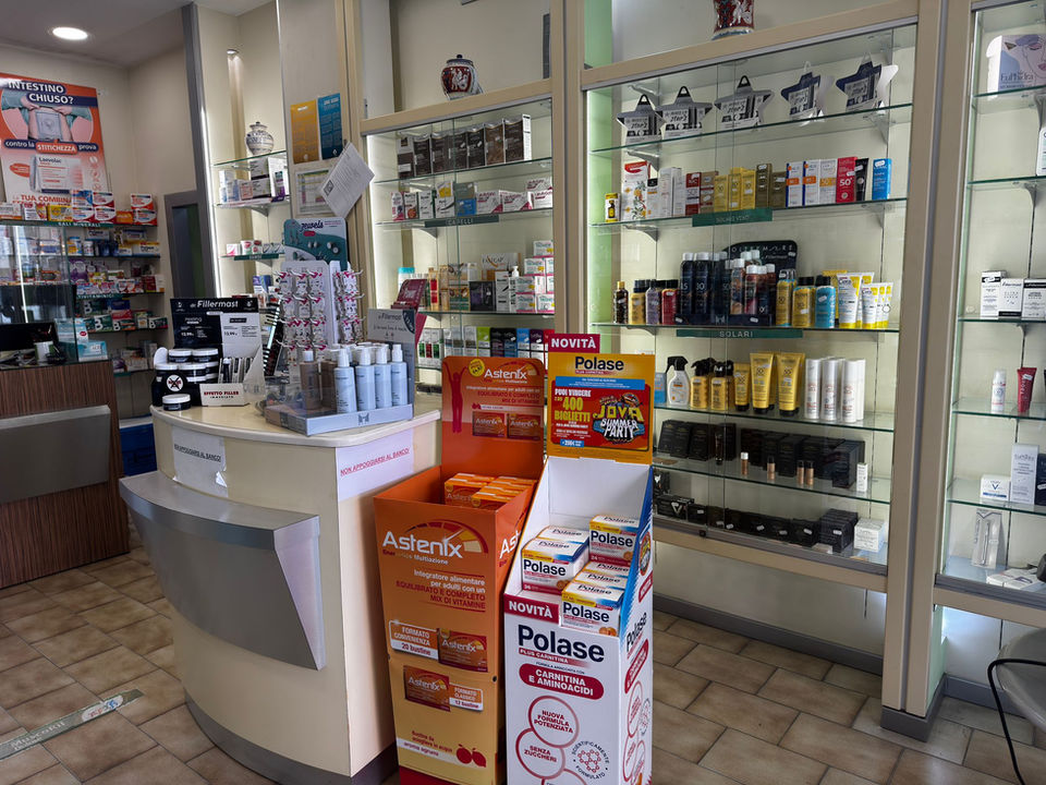 Interno di una farmacia con scaffali di prodotti e bancone.