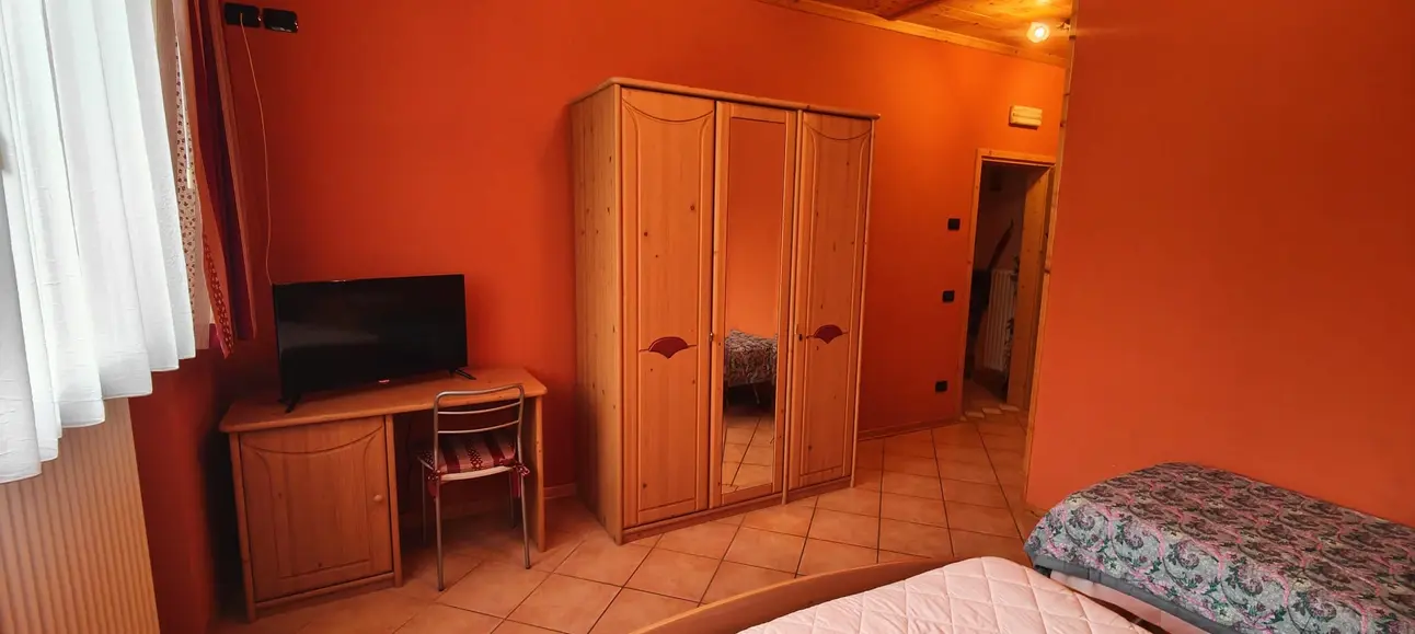 Camera da letto con pareti arancioni, armadio e scrivania