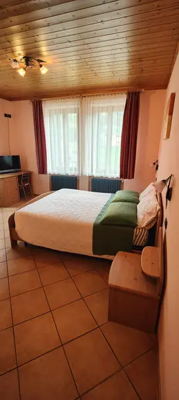 Camera da letto con letto matrimoniale e soffitto in legno.