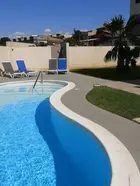 Piscina tradizionale con bordo curvo e lettini prendisole.
