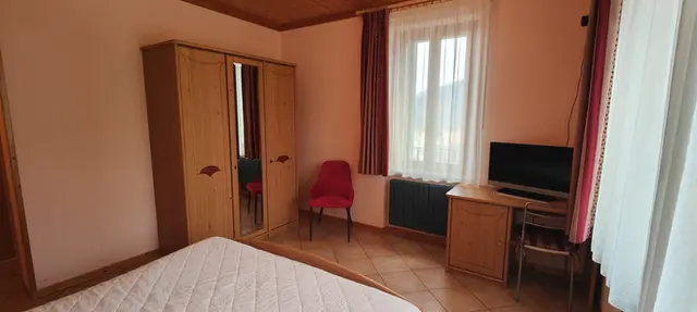 Camera da letto con armadio in legno, scrivania e TV.