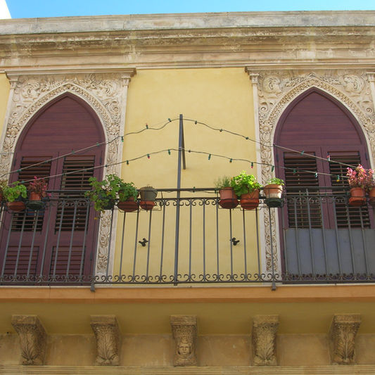 Balcone in alluminio con archi a sesto acuto e piante.
