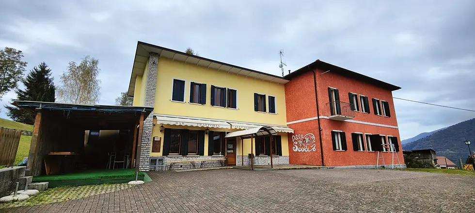 Esterno dell'edificio giallo e rosso con parcheggio.