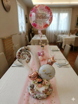 Centrotavola con palloncino Happy Birthday su tavolo imbandito.