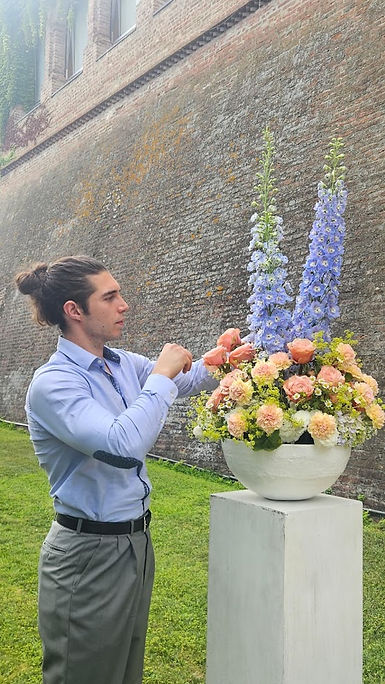 Fiorista allestisce composizione con rose e delphinium