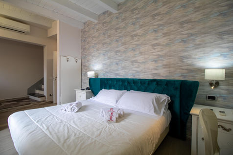 Letto matrimoniale con testiera turchese e lenzuola bianche.