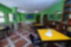 Aula studio con pareti verdi, tavoli gialli e librerie.