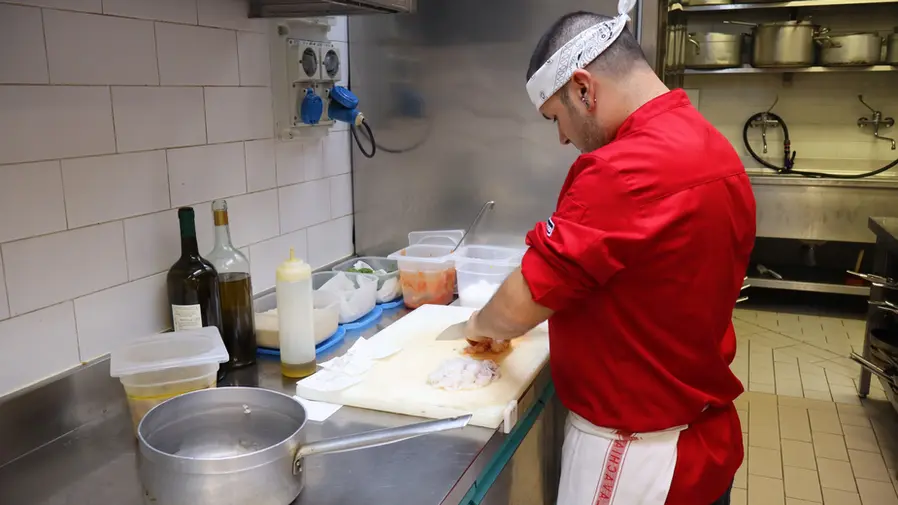 Chef in giacca rossa taglia ingredienti in cucina professionale