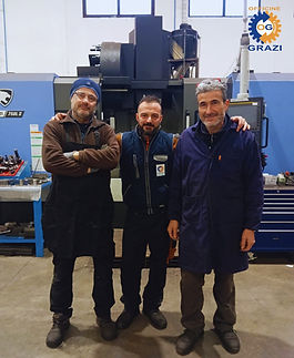 Tre dipendenti sorridenti davanti a un macchinario C.M.A.I.