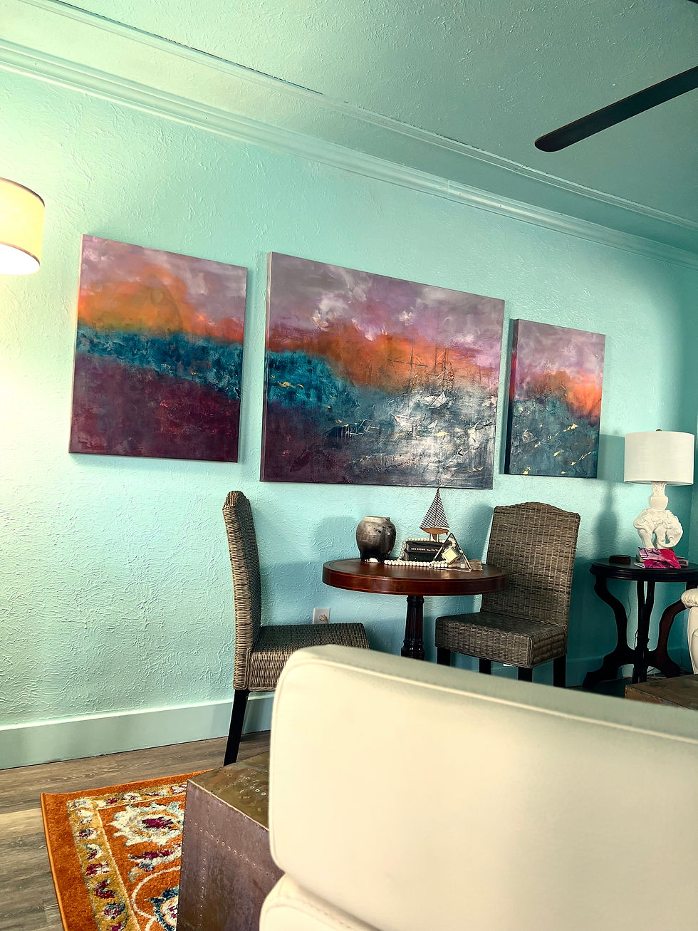 Partial view of the living room once the painting, The Places We Drift, was hung.  The painting is a large abstract seascape with sail boats driffing in the waters 