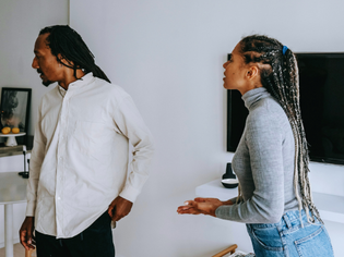 A couple having a tense conversation at home, with the woman speaking while the man looks away