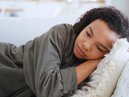 Teenage girl lying on a couch with her head resting on a pillow, appearing sad and withdrawn