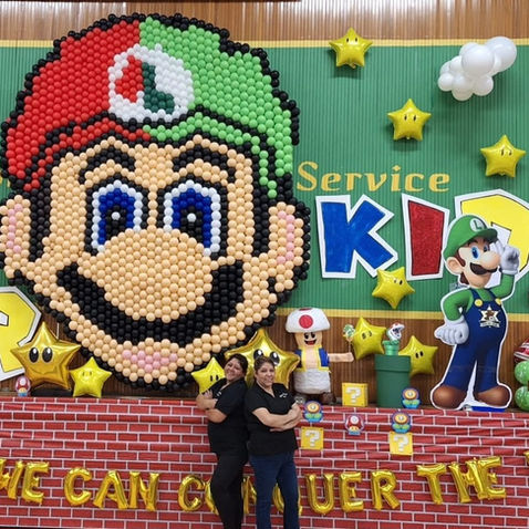 Super Mario Balloon Wall: Massive Super Mario themed structural balloon wall featuring Mario, Luigi, and star accents for a "999 For Kids" charity event.