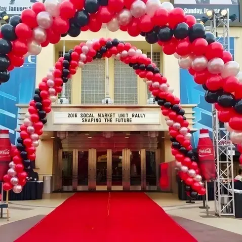 Red and Black Balloon Arch: Large-scale red and black spiral balloon arch framing a red carpet entrance for coca-cola's market rally corporate event.