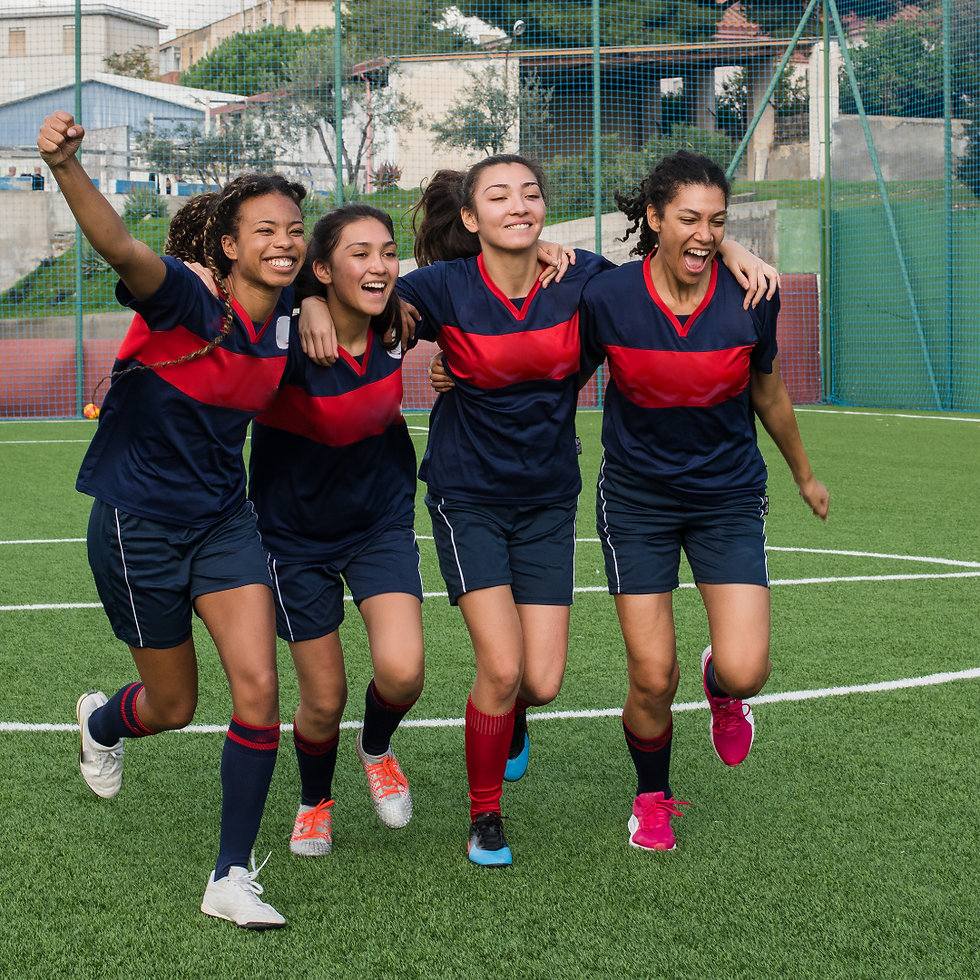 Four women footballers running and huddled together