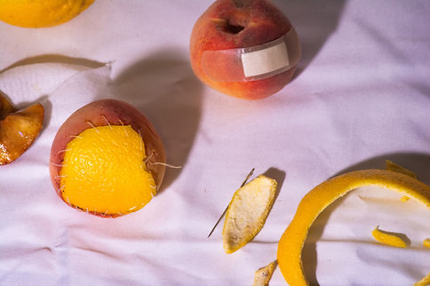The peach with the surgery lines from the previous image now has an orange skin sewn onto the top, creating a "Strange Fruit" similar to the artifacts created by American artist Zoe Leonard, born 1961.