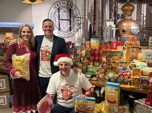 Paul, Like and Miranda surrounded by piles of donated food