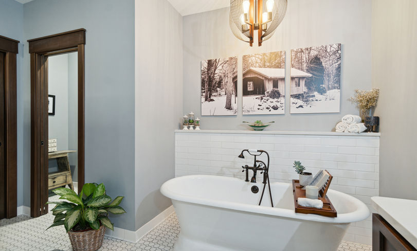 Elegant bathroom featuring a classic white clawfoot tub with oil-rubbed bronze fixtures and an industrial style chandelier.