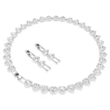 Un conjunto de joyería compuesto por un collar y aretes en forma de corazón, diseñados con un centro de cristal facetado rodeado por un halo de pequeñas piedras brillantes. El collar presenta un dije colgante en cadena fina, mientras que los aretes tienen un diseño compacto y elegante, ideal para complementar el conjunto con un estilo romántico y refinado.