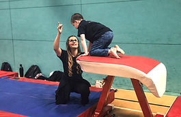 woman coaching boy gymnastics