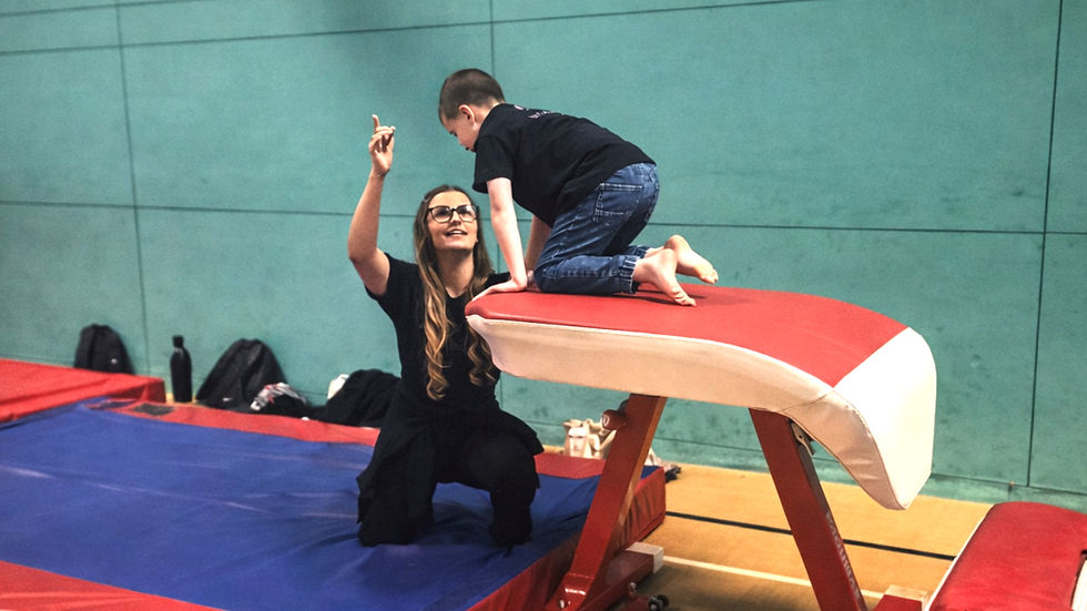 woman coaching boy gymnastics