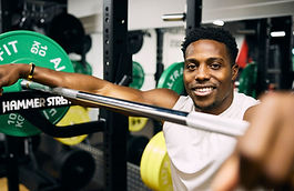 Harry Aikines-Aryeetey leaning on a barbell on a squat rack