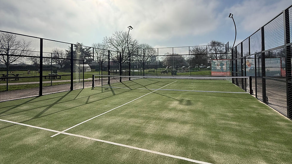 Empty outdoor padel court at Shobnall leisure complex with green artificial turf and metal mesh fencing on a sunny day.