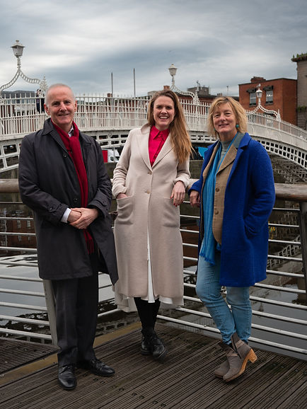 Grace O'Sullivan, Terry Reinkte & Ciarán Cuffe stand together by the Ha'Penny Bridge in Dublin.