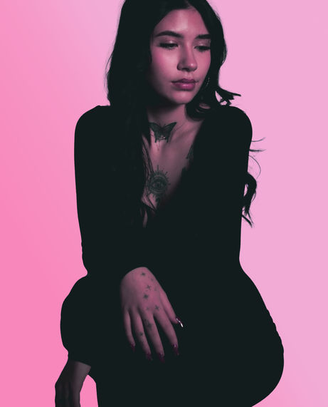 Woman in black dress against pink backdrop. Denver Portrait Photography.