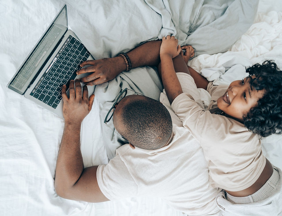 Man working from bed with child next to him