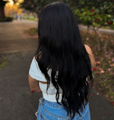 Woman with long black hair, wearing white top and denim shorts