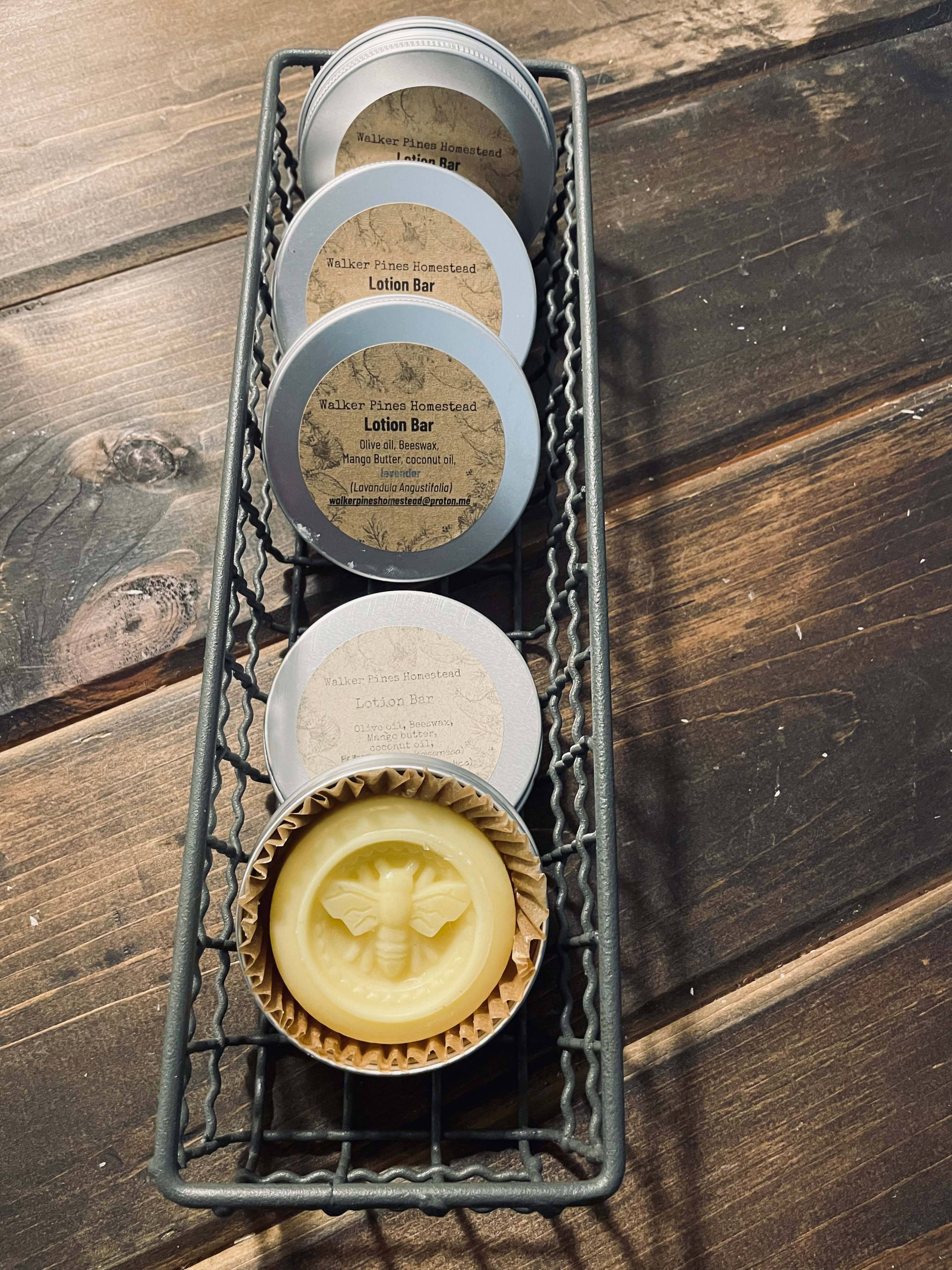 Four lotion bars in tins, one with a bee design, in a wire basket