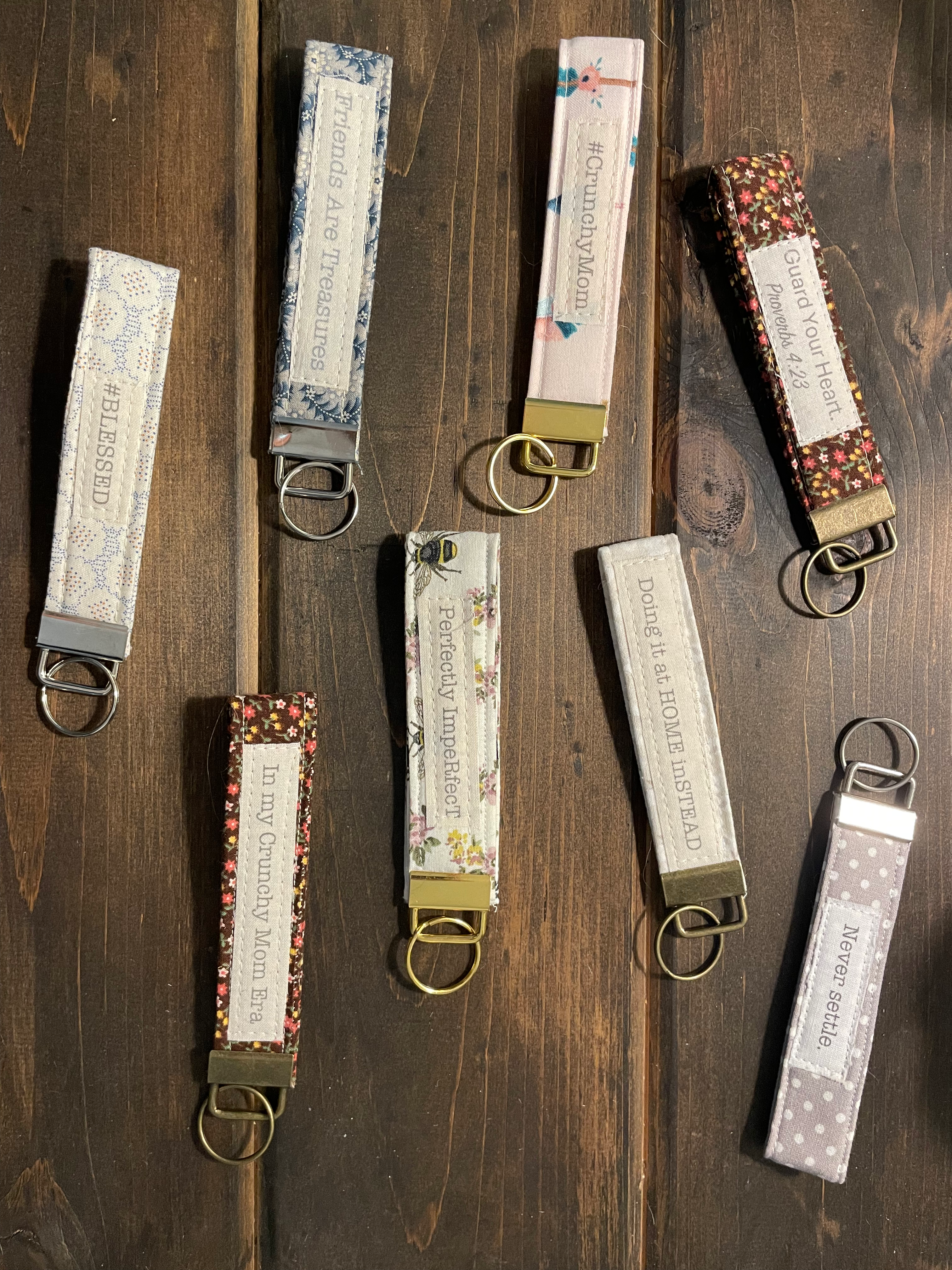 Eight fabric keychains with inspirational sayings on a wood surface