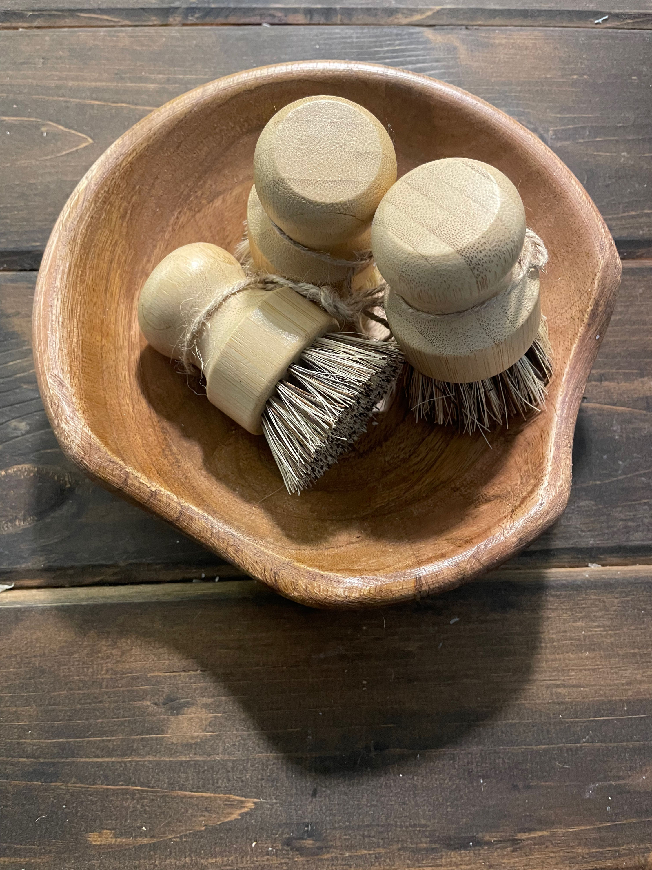 Three wooden cleaning brushes in a wooden bowl