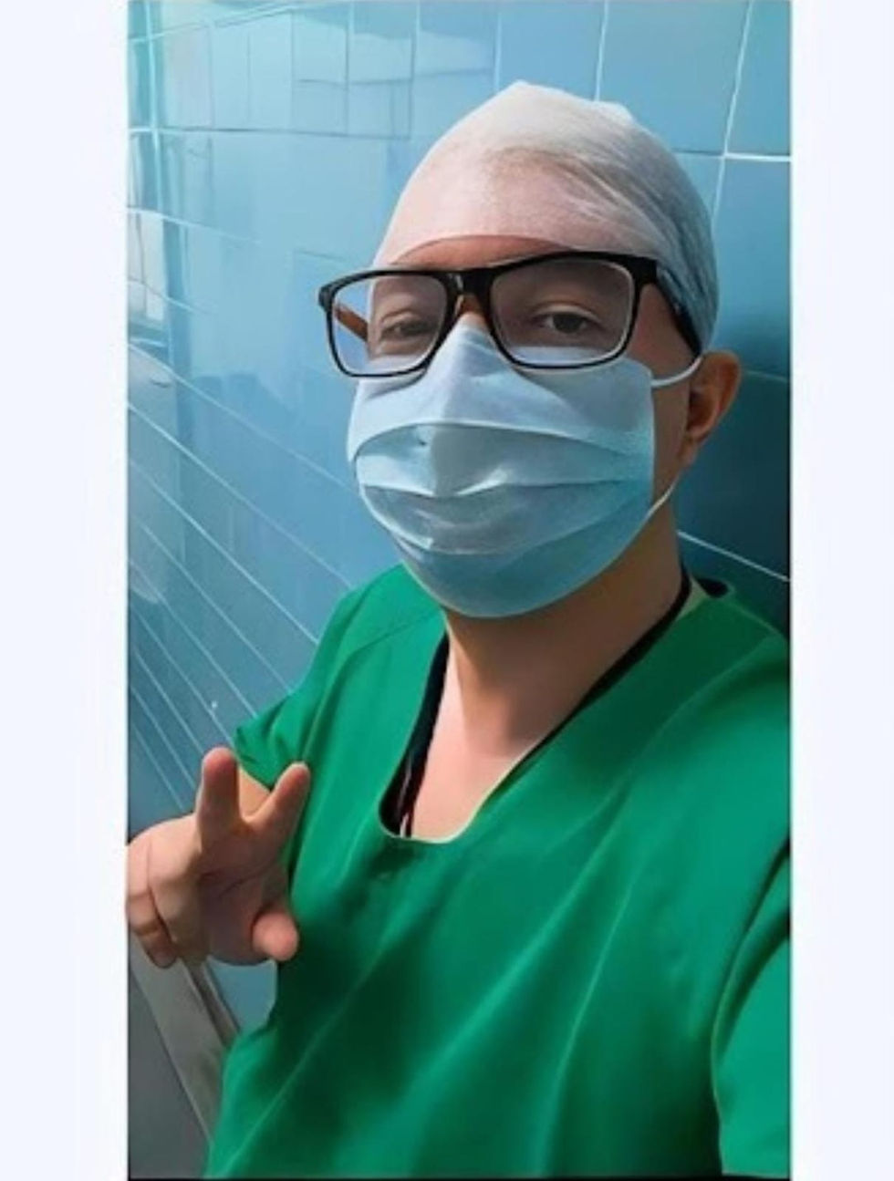 Retrato de médico com máscara e roupa cirúrgica em corredor de hospital, cores azul e verde, formato vertical (portrait).