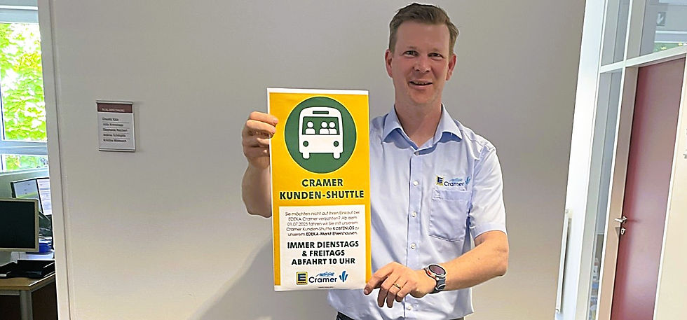 Marktbetreiber Sebastian Cramer zeigt das Haltestellenschild seines Shuttle-Angebots nach Ehlershausen.