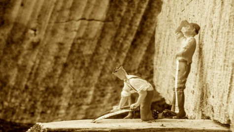 Zwei Spielzeugfiguren mit Sägen auf einem Stück Holz