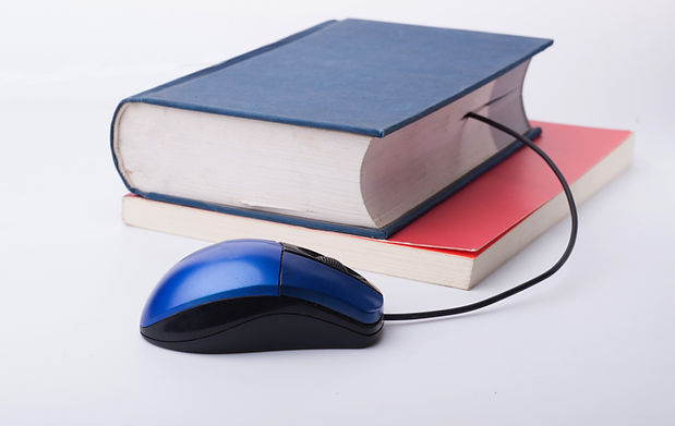 A blue hard cover book sits closed on top of a red soft cover book. The cord from a computer mouse appears to be coming from between the pages of the blue book.
