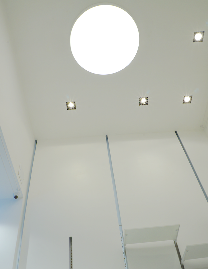 Detalle del sistema de iluminación del local Atavío, con luminarias empotradas y plafón circular que aportan uniformidad al diseño interior.