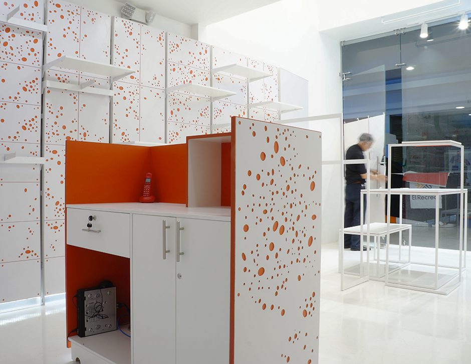 Mostrador de atención al cliente en la tienda Atavío, con estructura blanca, interior rojo y detalles gráficos de puntos diseñados por IKONEstudio.