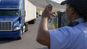 Security officer directing a delivery truck entering a secure industrial or logistics site through a gated checkpoint and to scan them in with the VisitMe scanner.