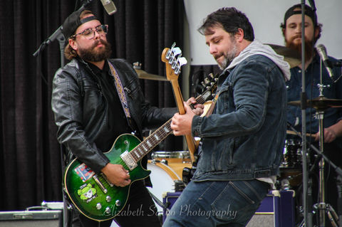 Two guitarists face each other while playing, as if to duel one another.