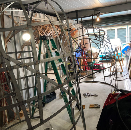 Side angle of the arch's metal interior sitting in two main pieces inside a truck, waiting for assembly.